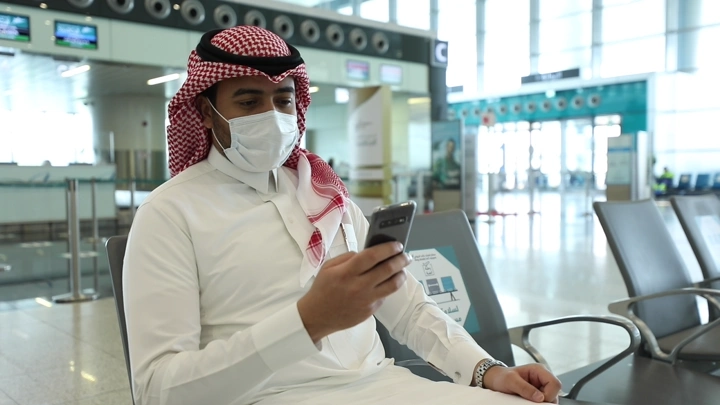 رجل يجلس في مطار يستخدم هاتفه، لقطة طبيعية.