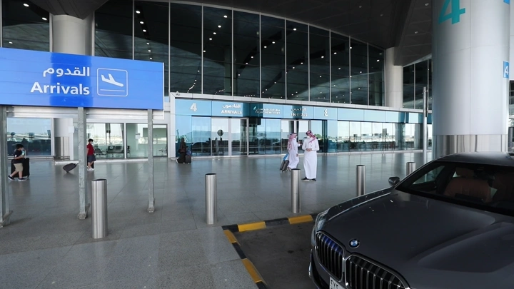 مدخل صالة الوصول في المطار مع سيارة متوقفة، لقطة خارجية.