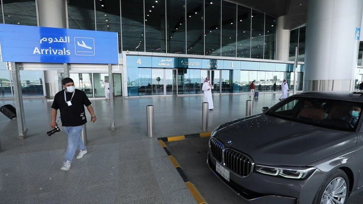 رجل يركب سيارة من المطار  عند بوابة الوصول في المطار، لقطة نهارية.