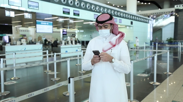 رجل في مطار يحجز سيارة باستخدام هاتفه، لقطة داخلية.