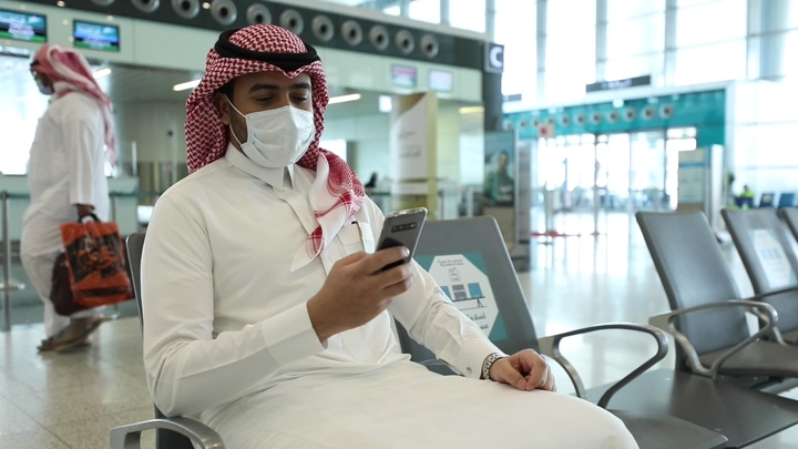 رجل يجلس في مطار يستخدم هاتفه، لقطة طبيعية.