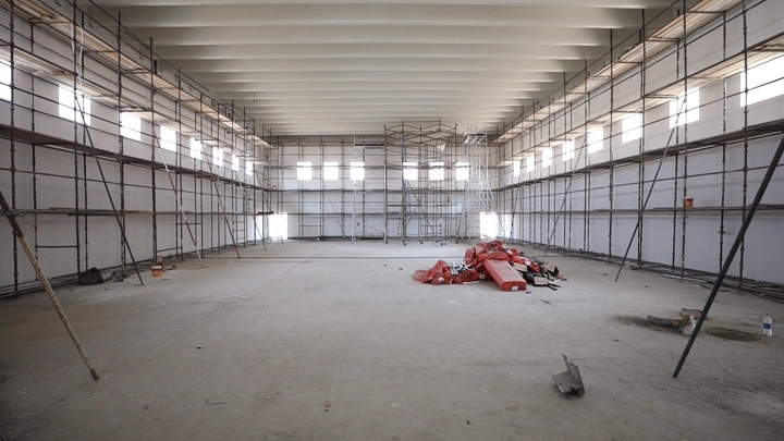 موقع بناء داخلي مع سقالات وأرضية ترابية، لقطة واسعة.