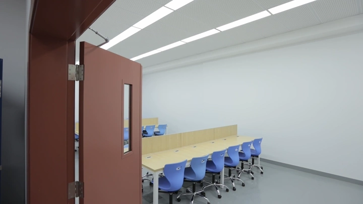 فصل دراسي حديث بمقاعد زرقاء داخل مدرسة، لقطة من الباب.