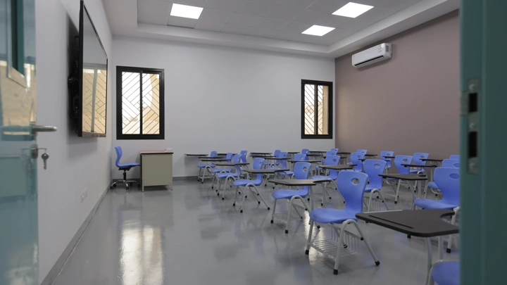 فصل دراسي حديث بمقاعد زرقاء وإضاءة طبيعية، لقطة داخلية.