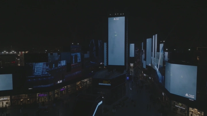 شاشات إعلانية مضيئة في البوليفارد بالرياض ليلاً، لقطة جوية.