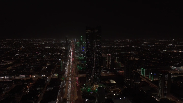أبراج الرياض مضاءة ليلاً مع العلم السعودي، لقطة جوية.