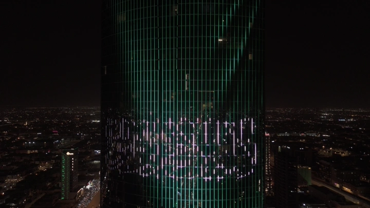 العلم السعودي على برج في الرياض ليلاً، لقطة جوية.