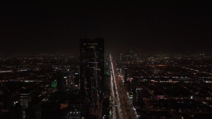 أبراج الرياض مضاءة في الليل مع علم السعودية، لقطة جوية.