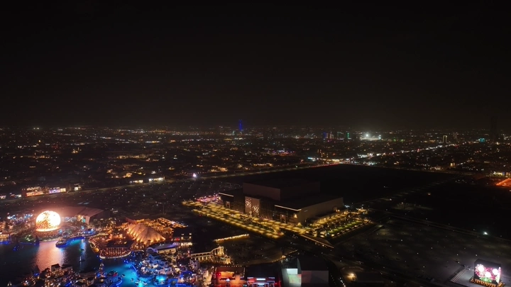 منظر جوي لمدينة الرياض ليلاً مع أضواء ساطعة وملعب المملكة أرينا.