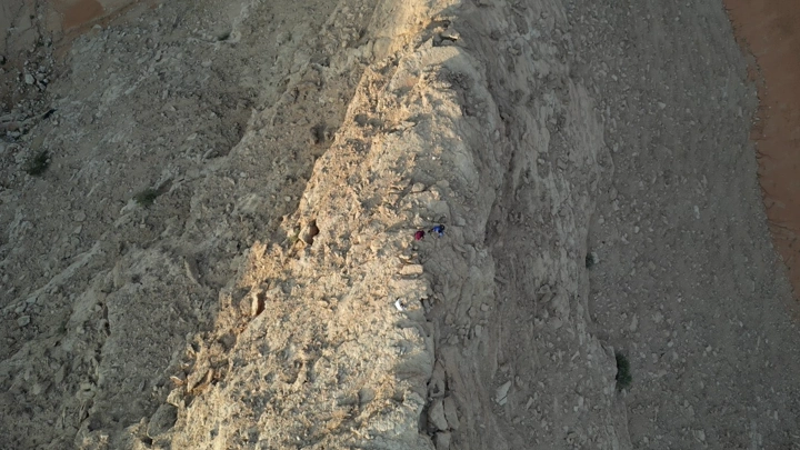 أشخاص يتسلقون جبلًا صخريًا، لقطة جوية.