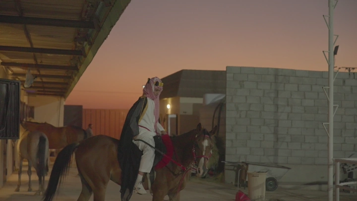 راكب خيل في إسطبل عند الغروب، لقطة جانبية.