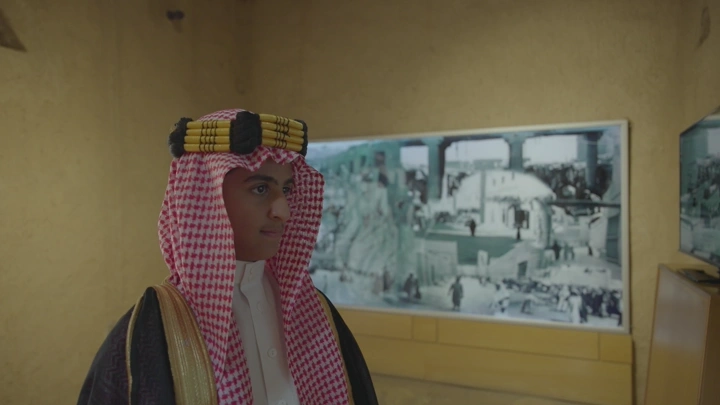 رجل يرتدي الزي السعودي يتأمل الشاشات داخل قصر المصمك بالرياض، لقطة داخلية.