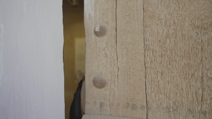 شاب بزي سعودي يفتح باب خشبي قديم في قصر المصمك في الرياض، لقطة مقربة.