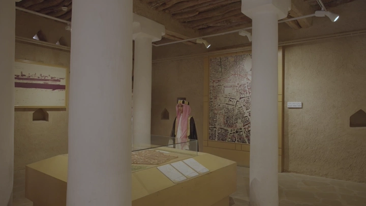 شاب سعودي يتجول داخل قصر المصمك بالرياض، صورة داخلية تعرض معرضًا تاريخيًا.