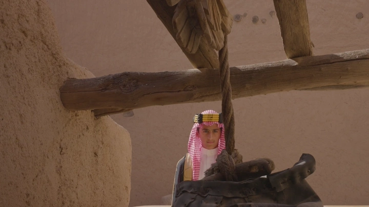 شاب يرتدي الزي السعودي في قصر المصمك عند البئر في الرياض، لقطة مقربة.