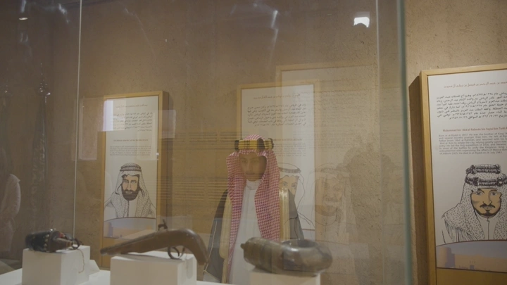 شاب يتأمل معروضات تاريخية في قصر المصمك بالرياض، لقطة داخلية.