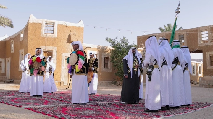 مجموعة رجال سعوديين يؤدون رقصة السامري في ساحة تراثية، تصوير خارجي.