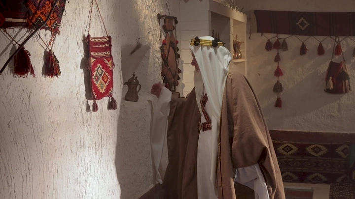 رجل كبير بالسن بلباس تراثي سعودي في غرفة تراثية، لقطة داخلية.