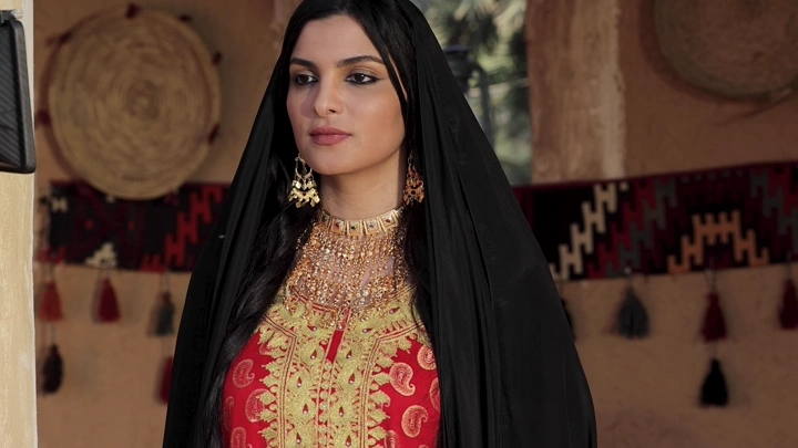 امرأة ترتدي لباس تراثي سعودي في بيت طيني، لقطة قريبة.