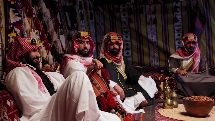 رجال يرتدون الزي السعودي التقليدي في خيمة مزينة، لقطة داخلية.