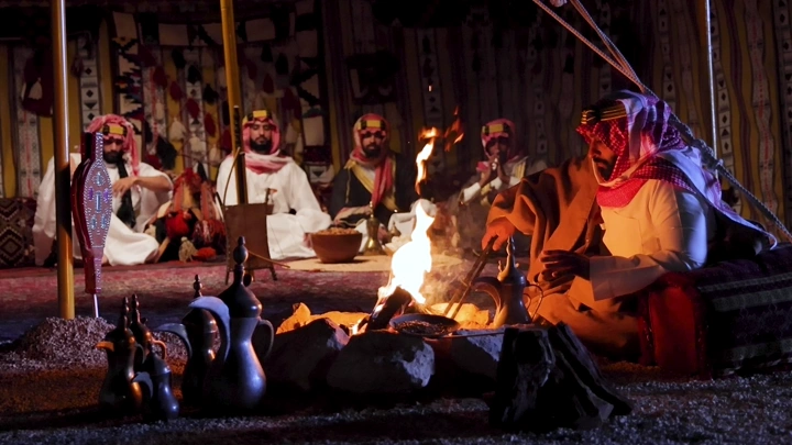 رجال بلباس تراثي سعودي في خيمة، لقطة ليلية.
