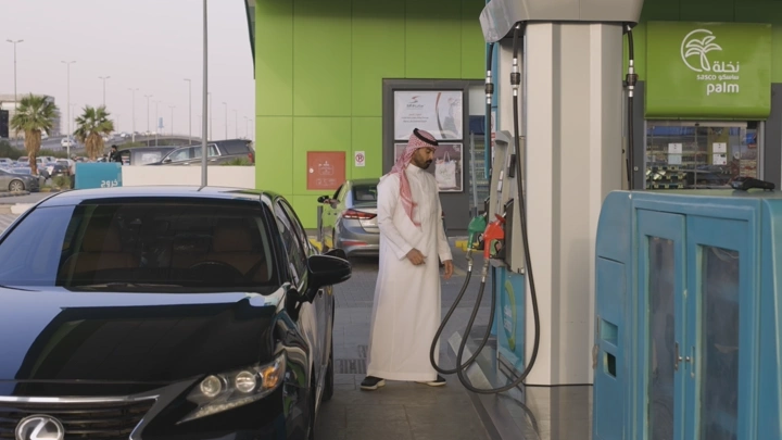 رجل يملأ سيارته بالوقود في محطة بنزين، لقطة نهارية.