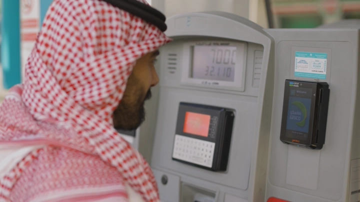 رجل يرتدي شماغ يعبئ الوقود في محطة بنزين، لقطة مقربة.