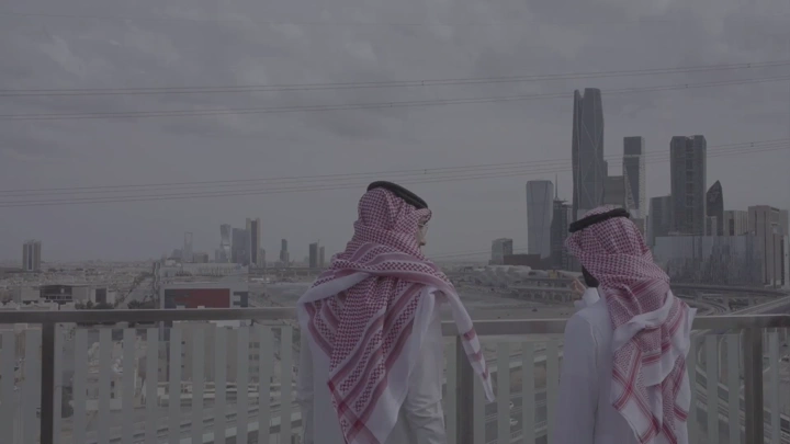 شباب يتحدثون أمام المدينة المالية كافد في الرياض، لقطة من الخلف.