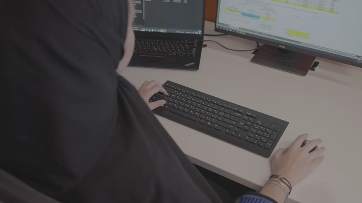 امرأة تعمل على مكتب مع شاشات، لقطة من الأعلى.