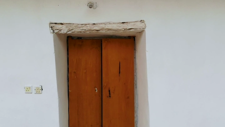 فتاة تخرج من باب خشبي تراثي في رجال ألمع في عسير، لقطة جوية.