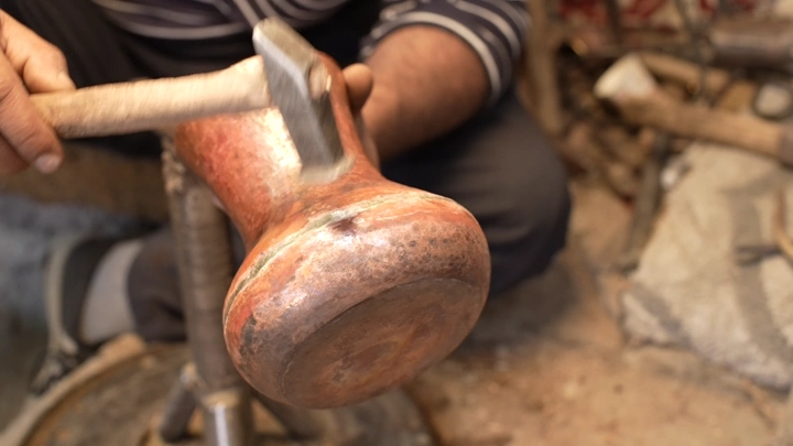 حرفي يصنع دلة نحاسية في ورشة تقليدية، لقطة مقربة.