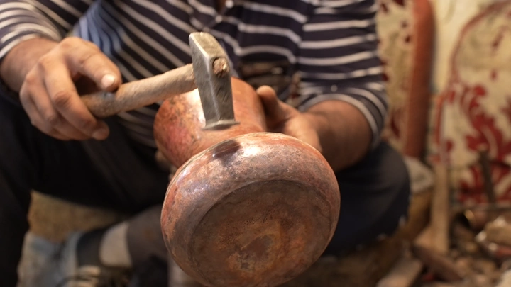 حرفي يصنع دلة سعوية بمطرقة يدوية، لقطة مقربة.