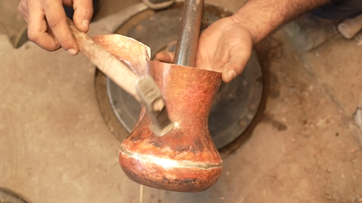 صناعة دلة نحاسية يدوياً في ورشة، لقطة مقربة.