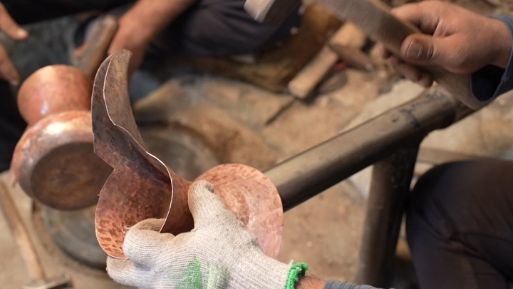 صناعة دلة تقليدية من النحاس في ورشة حرفية، لقطة مقربة.