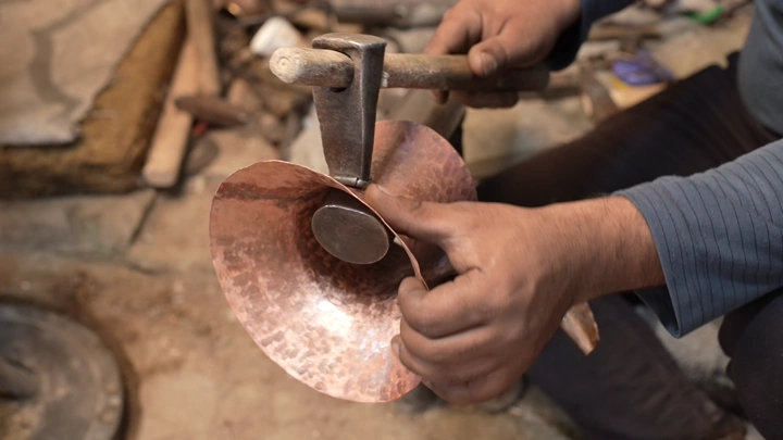 صانع يدوي يشكل النحاس لصنع دلة، لقطة مقربة.