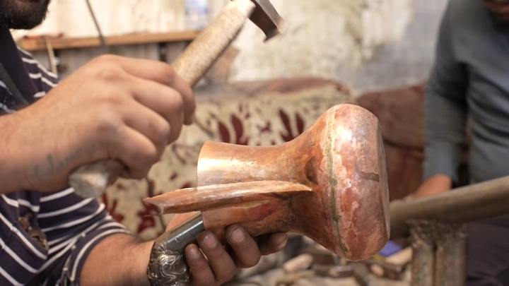 حرفي يصنع دلة نحاسية في ورشة، لقطة مقربة.