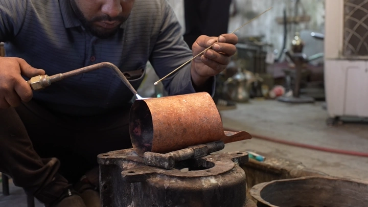 حرفي يصنع دلة نحاسية في ورشة تقليدية، لقطة مقربة.