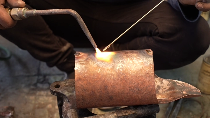 عملية لحام النحاس في ورشة عمل، لقطة مقرّبة.