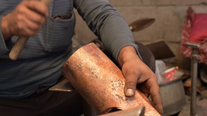 حرفي يصنع دلة نحاسية في ورشة، لقطة مقربة.