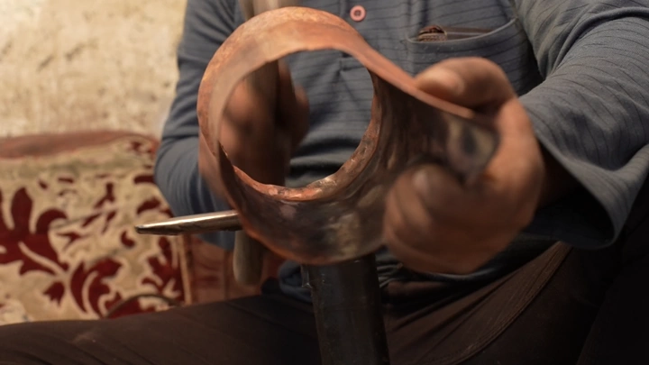 حرفي يصنع دلة يدوية في ورشة تقليدية، لقطة مقربة.