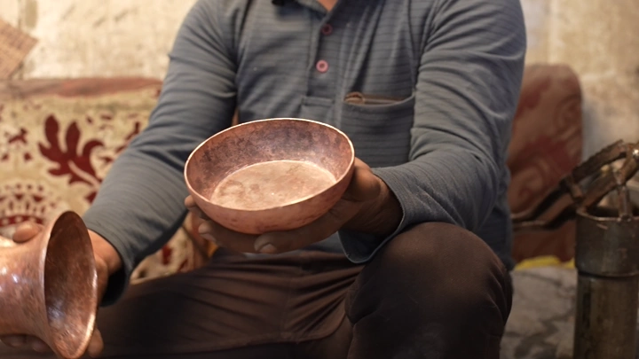 حرفي يصنع دلة نحاسية في ورشة، لقطة قريبة.