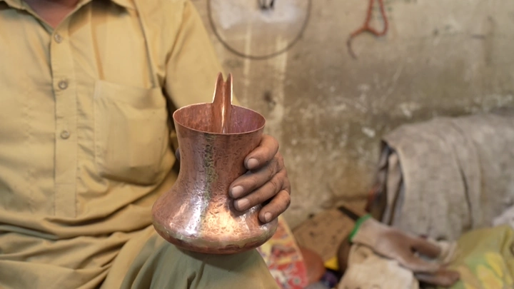 حرفي يصنع دلة نحاسية في ورشة، لقطة قريبة.