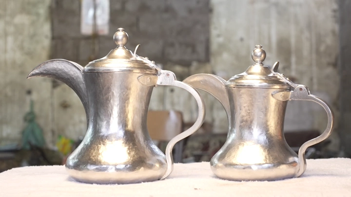 دلتان فضيتان موضوعتان على طاولة في ورشة، لقطة قريبة.