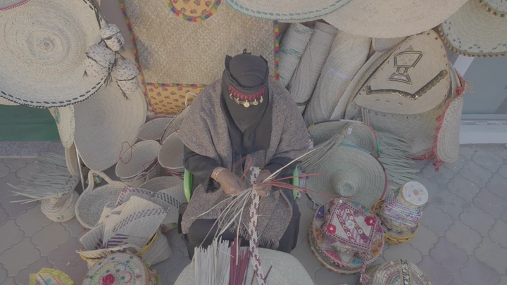 امرأة تصنع منتجات الخوص في الهواء الطلق، لقطة من الأعلى.