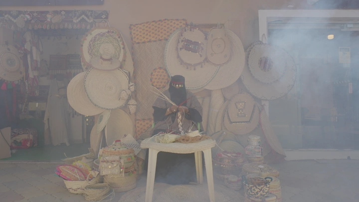 امرأة تصنع منتجات الخوص في ورشة تقليدية، لقطة أمامية.