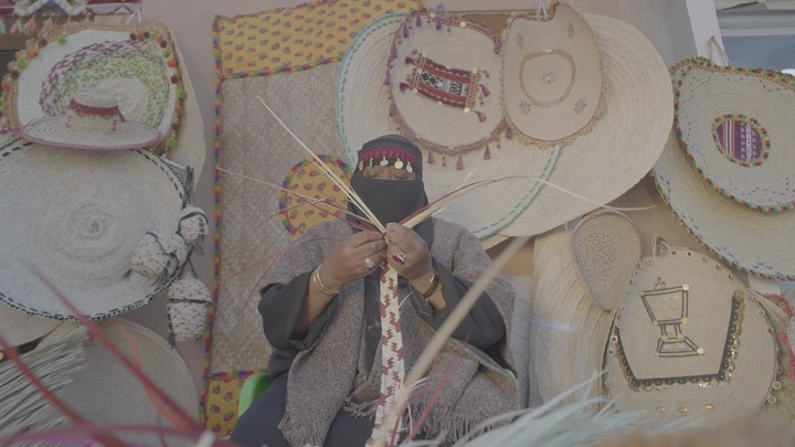 حرفية يدوية تصنع منتجات الخوص في سوق تقليدي، لقطة مقربة.