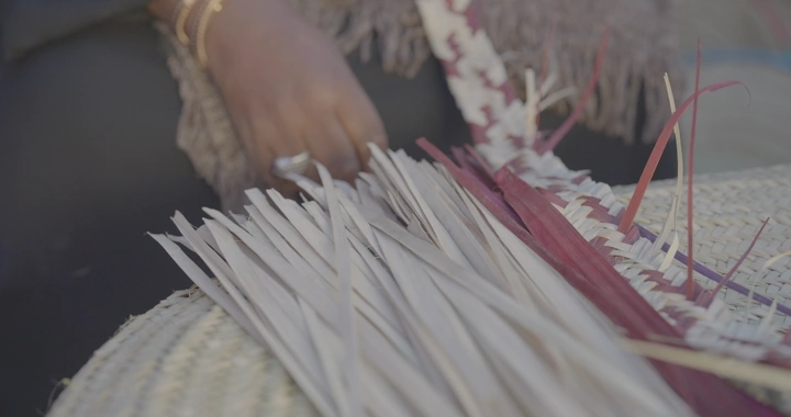 امرأة تنسج سعف النخيل يدويًا، لقطة مقربة.