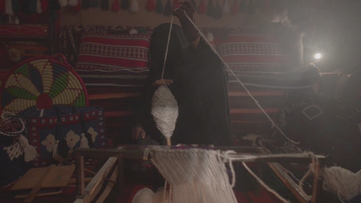 امرأة تنسج السدو في غرفة عمل، لقطة داخلية.