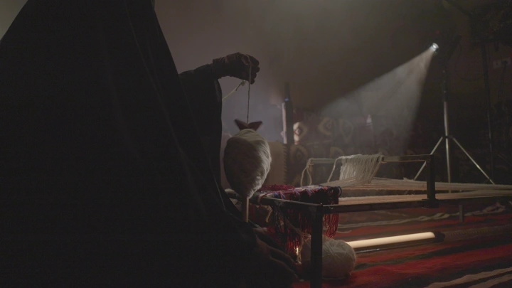 حياكة السدو في خيمة تقليدية، إضاءة خافتة.