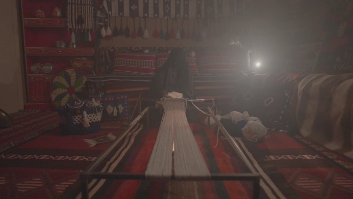 امرأة تنسج خيوط السدو، إضاءة خافتة، منظر أمامي.